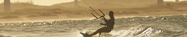 Practicante de kitesurf realizando una maniobra sobre una ola