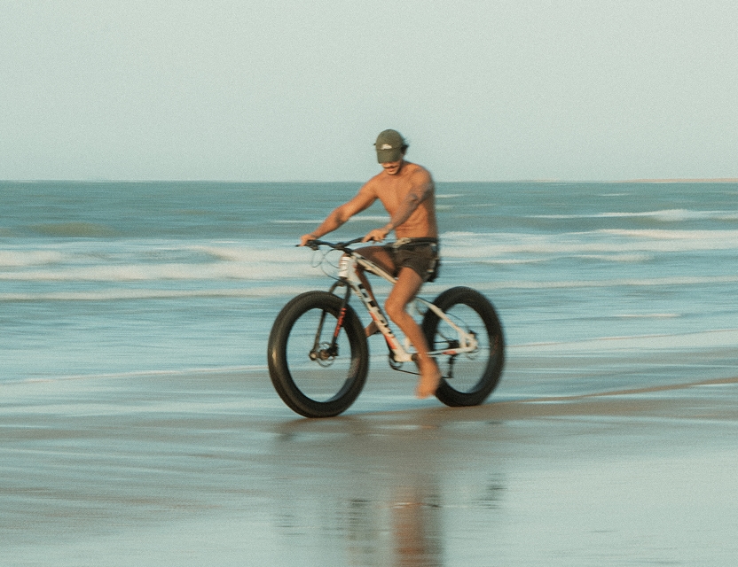 Turista com bicicleta na praia de Icaraizinho, passeio disponível no Club de Mar